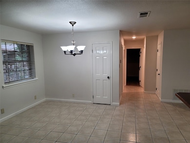 Unfurnished dining area with a textured ceiling, a chandelier, and light tile patterned floors