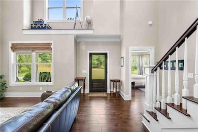 Entryway featuring a towering ceiling, dark wood finished floors, and stairway