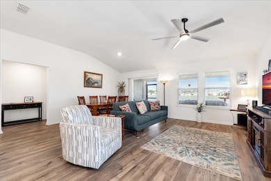 Living room featuring lofted ceiling, wood finished floors, and ceiling fan