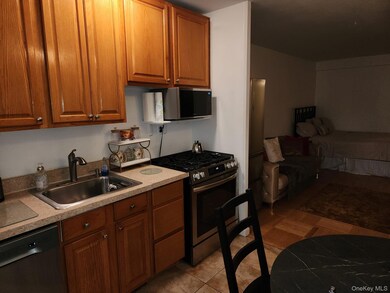 Kitchen with appliances with stainless steel finishes, brown cabinetry, light countertops, light tile patterned floors, and open floor plan