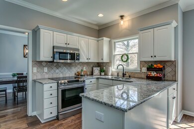 This white kitchen features new granite, stainless appliances, new lighting.