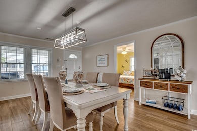 Dining room featuring crown molding, wood finished floors, baseboards, and a textured ceiling