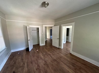Unfurnished bedroom with a textured ceiling, dark wood-type flooring, and a closet