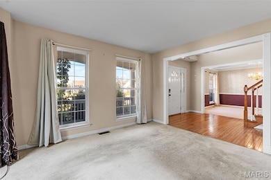 Foyer with wallpapered walls, carpet, a chandelier, wood finished floors, and stairway