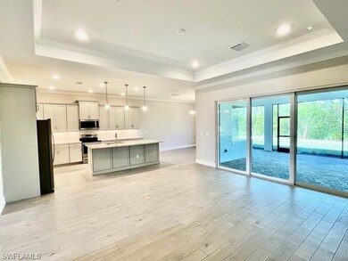 Kitchen featuring a raised ceiling, stainless steel appliances, open floor plan, a sink, and ornamental molding