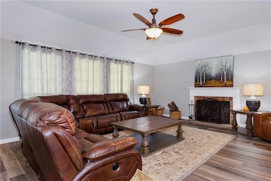 Living room with a fireplace, wood finished floors, and ceiling fan