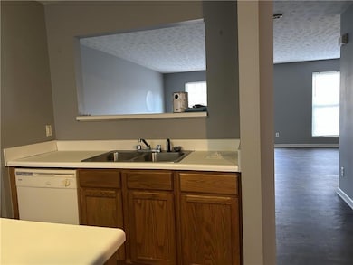 Kitchen with white dishwasher, a textured ceiling,