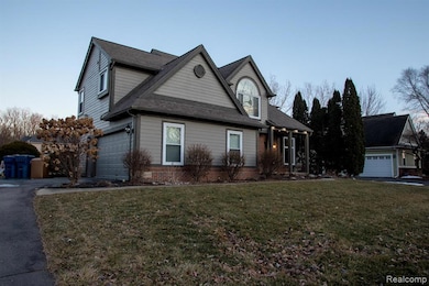 View of front facade with a front yard, brick siding, and driveway