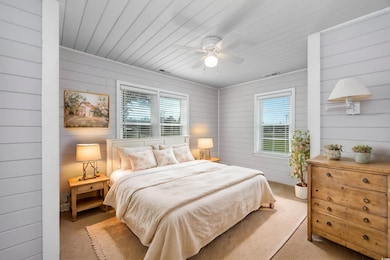 Bedroom with ceiling fan, light carpet, wooden wal