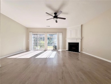 Unfurnished living room featuring a fireplace, wood finished floors, and ceiling fan