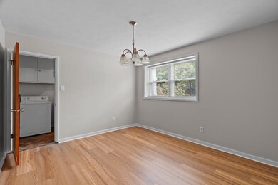 Unfurnished dining area with washer / clothes dryer, light wood-style floors, and a chandelier