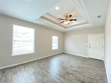 Spare room featuring a ceiling fan, baseboards, visible vents, wood finished floors, and a raised ceiling