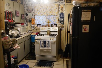 Kitchen featuring light tile patterned floors, white appliances, and gray cabinets
