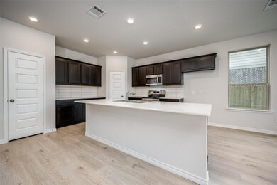 Kitchen with a kitchen island with sink, light woo