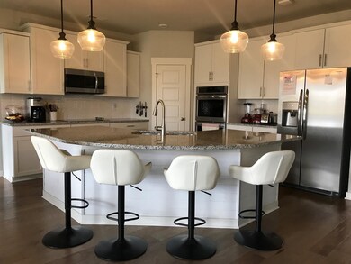 Not actual home - same floorplan Kitchen has huge island, SS appliances, tile backsplash and hardwood flooring