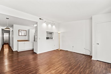 Unfurnished living room with dark wood finished floors and track lighting