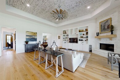 Living area with a raised ceiling, light wood-style floors, a high end fireplace, and recessed lighting