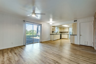 Unfurnished living room featuring light wood finished floors, crown molding, wooden walls, and ceiling fan