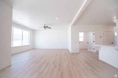 Large family room  adjoining dining area and kitchen with ceiling fan.