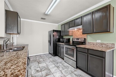 Kitchen featuring light stone countertops, sink, ornamental molding, and black appliances