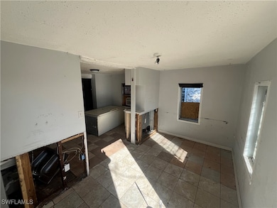 Unfurnished living room featuring a textured ceili