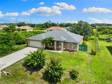 View of front facade with concrete driveway, stucco siding, roof with shingles, and view of wooded area