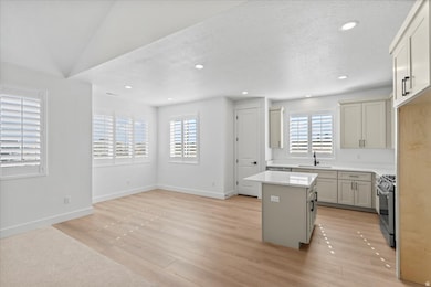 Kitchen with a kitchen island, stainless steel range with gas cooktop, recessed lighting, light wood-style floors, and a textured ceiling