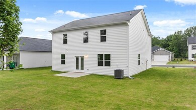 Back of house featuring a garage, a lawn, and a patio area