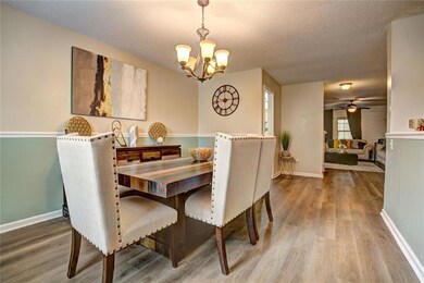 Dining area featuring wood finished floors, a chandelier, a textured ceiling, and a ceiling fan