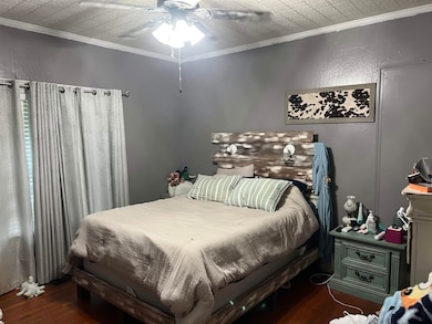 Bedroom with wood finished floors, ornamental molding, and ceiling fan