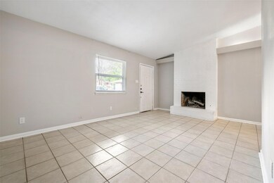 Unfurnished living room featuring light tile patterned flooring and a brick fireplace