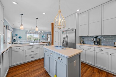 Kitchen featuring stainless steel refrigerator with ice dispenser, a chandelier, light countertops, dark wood finished floors, and recessed lighting