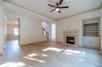 Unfurnished living room with ornamental molding, a glass covered fireplace, light wood-style floors, a ceiling fan, and stairway