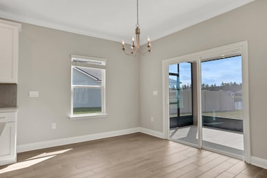 Unfurnished dining area with healthy amount of natural light, light wood finished floors, a chandelier, and ornamental molding