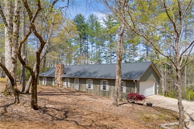 Ranch-style house featuring driveway, roof with shingles, a garage, and a chimney