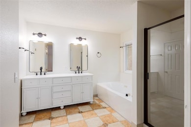 Bathroom featuring a garden tub, double vanity, and a textured ceiling