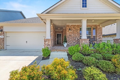 View of front of house featuring covered porch, brick siding, driveway, and a garage