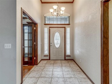 Tiled foyer with an inviting chandelier and crown 