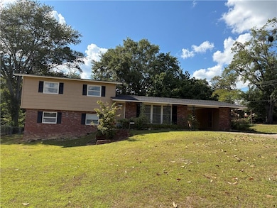 Split level home featuring brick siding, a front yard, and a carport