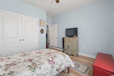 Bedroom featuring a closet, baseboards, wood finished floors, and a ceiling fan