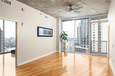 Empty room featuring wood finished floors, healthy amount of natural light, a ceiling fan, floor to ceiling windows, and a view of city
