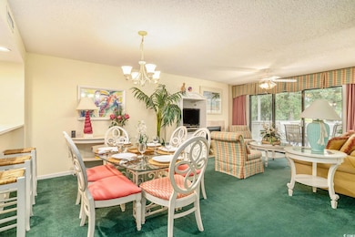 Dining room with carpet, a chandelier, a textured ceiling, and a ceiling fan