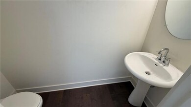 Half bath with baseboards, wood finished floors, toilet, and a sink