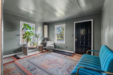 Living area with a baseboard radiator and ornamental molding