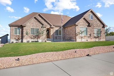 View of front of home with stone siding, a front lawn, and a shingled roof