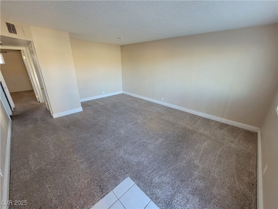 Spare room with light colored carpet, a textured ceiling, and light tile patterned floors