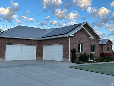 View of property exterior with brick siding, driveway, a garage, and solar panels