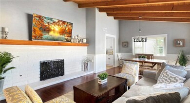 Beautiful Formal Living Room and Dining Room with Vaulted Open Beam Ceiling, Engineered Wood Flooring, Wainscotting on all Walls, Massive White Brick Fireplace with Mantel, and Sliders Leading to Private Gated Front Yard