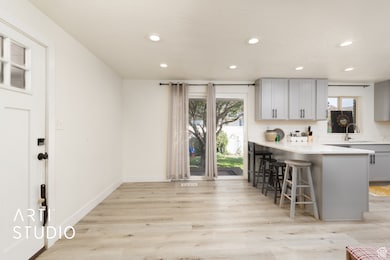 Kitchen featuring a breakfast bar, light wood-style flooring, recessed lighting, light countertops, and gray cabinets