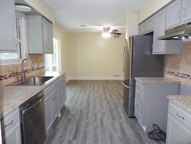 Kitchen featuring decorative backsplash, light countertops, appliances with stainless steel finishes, gray cabinetry, and a textured ceiling